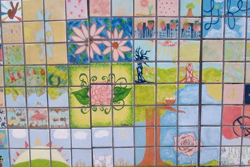 Close up of an arrangement of tiles with flowers, a tree, and other nature scenes painted
