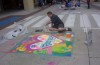 Artist kneeling by a six-by-six foot foster care chalk mural