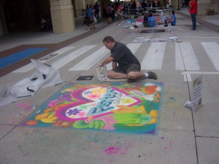 Artist kneeling by a six-by-six foot foster care chalk mural