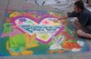 Roger Whiting painting a chalk mural of a heart with "Foster Care" written on the inside