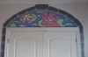 Above a closet door is a painting of a stained glass window with a flower and lily pad.