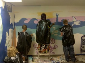 Teenagers wearing black garbage bags painting